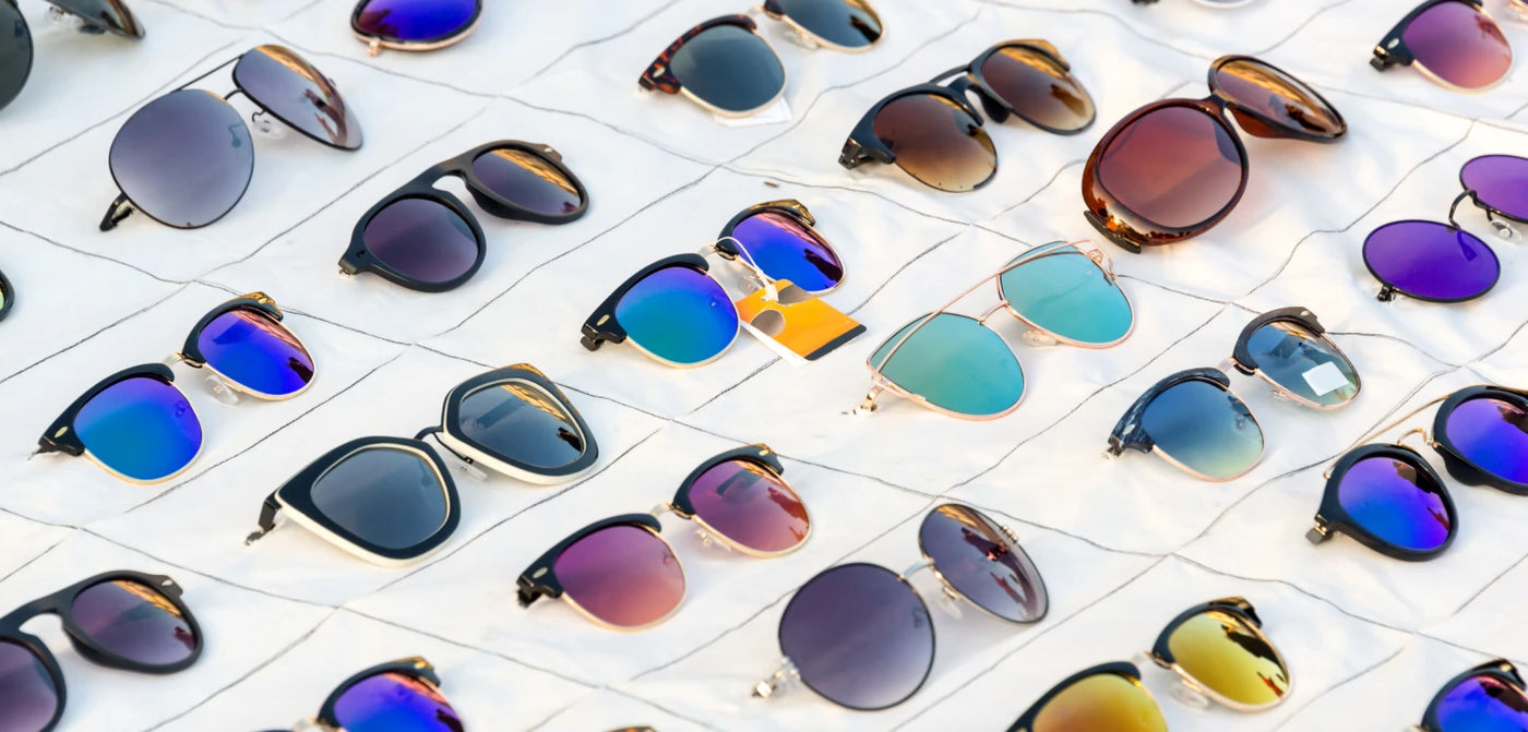 A variety of stylish sunglasses with different frame shapes and lens colors displayed neatly on a white surface.