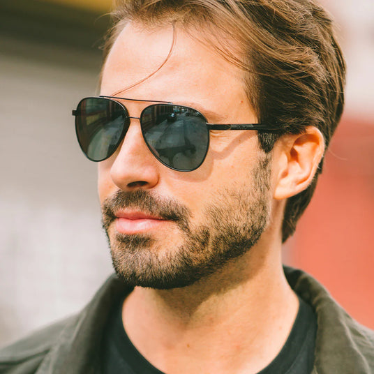 smiling man wearing revo arthur re1109 metal aviator sunglasses with dark grey lenses