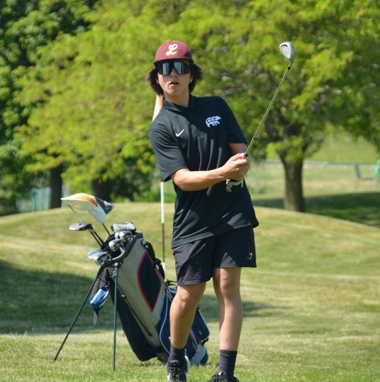 young man wearing a red hat and black sunglasses golfing on a beautiful golf course in california