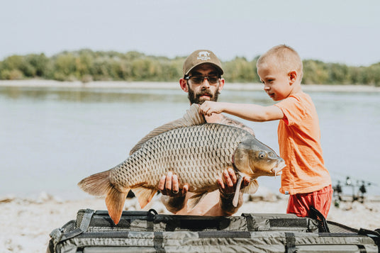 angler teahcing son how to fish on the lake after making a big catch