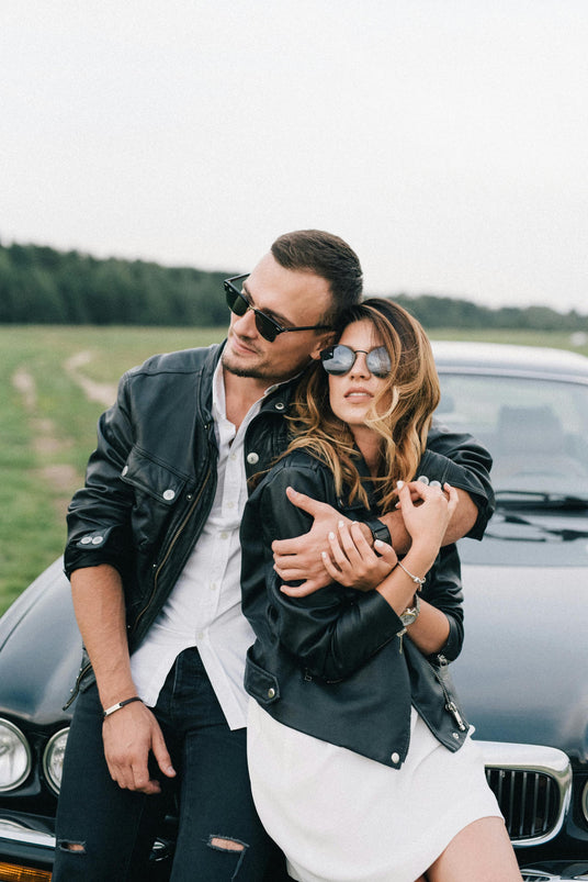 beautiful, affectionate couple resting on a jaguar car on a bright, sunny day with sunglasses