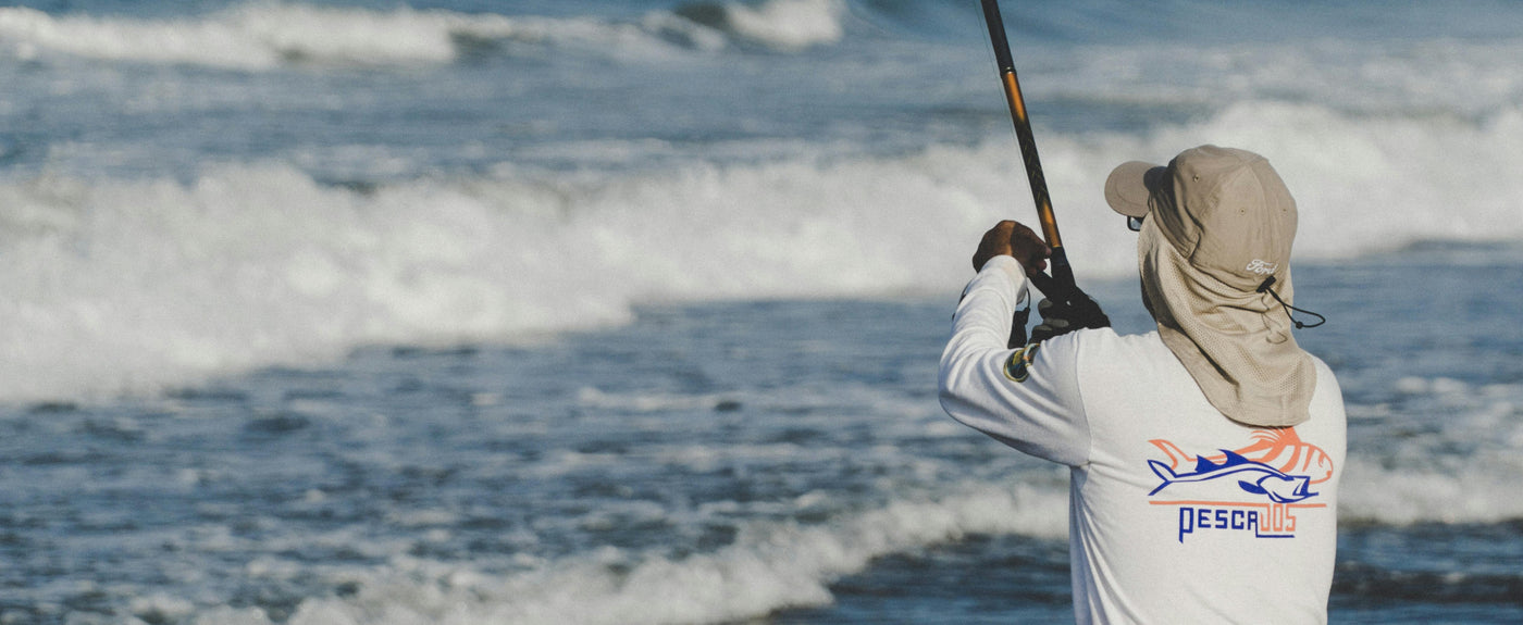 man fishing on beach with a fishing tshirt and hat