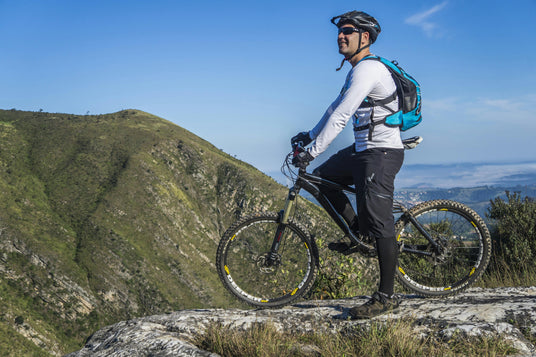 cyclist on a beautiful green mountaintop wearing helmet and oakley sunglasses