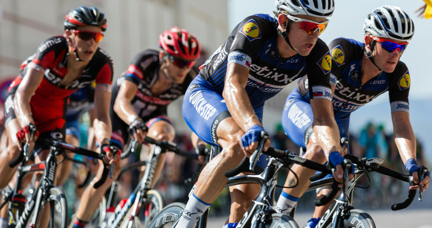 four men racing on bicyles wearing sunglasses and helmets