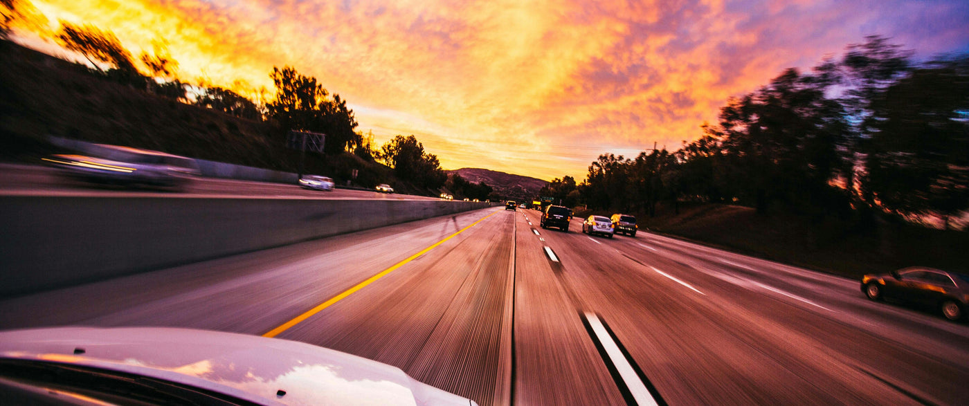 cars driving fast down a highway at sunset