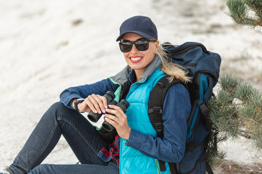 smiley women hiker outdoors on snowy pass with backpack and binoculars